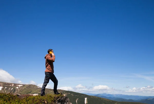 Mannen på bergets topp talar av mobiltelefon — Stockfoto