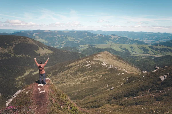 Hombre de pie en la cima de la montaña y mirando al horizonte —  Fotos de Stock