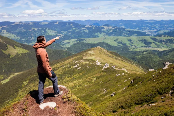 Mann steht auf Berggipfel und zeigt auf Horizont — Stockfoto