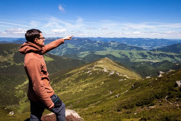 Dağın tepesinde duran ve ufukta işaret eden adam — Stok fotoğraf