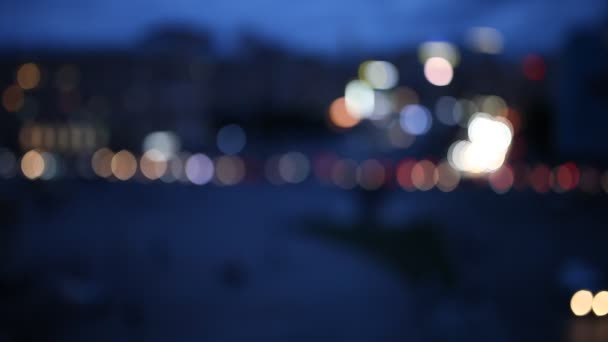 Fuera de foco fondo con borrosas luces desenfocadas de la ciudad y gente caminando en la plaza — Vídeos de Stock