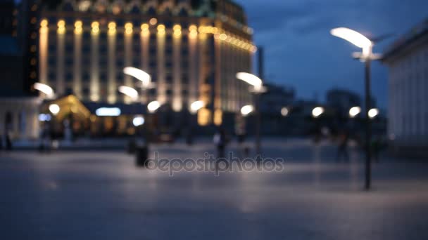 Out of focus background with blurry unfocused city lights and people walking at the square — Stock Video