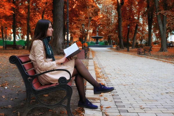 Mujer joven leyendo libro en el parque de otoño — Foto de Stock