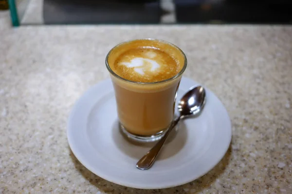 Copo de macchiato na mesa no interior do café — Fotografia de Stock