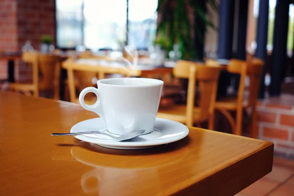 White cup of coffee over blurred cafe interior — Stock Photo, Image