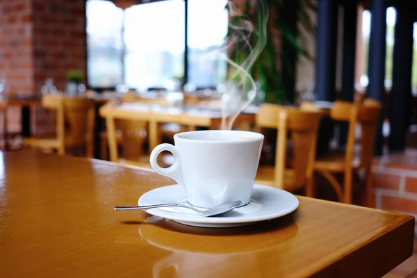 Біла чашка кави над розмитим інтер'єром кафе — стокове фото
