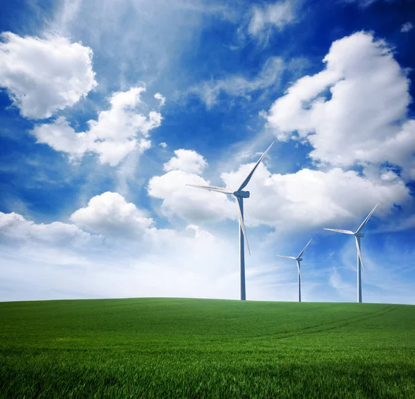 Ветряная электростанция на зеленой травяной лужайке над голубым солнцем с — стоковое фото