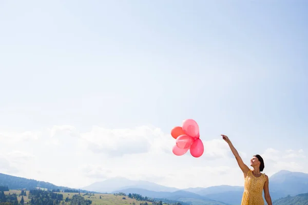 Jovem menina feliz segurando balões vermelhos sobre o céu azul — Fotografia de Stock