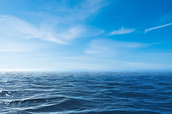 Cielo azzurro nuvoloso che parte per orizzonte sopra una superficie azzurra del mare — Foto Stock