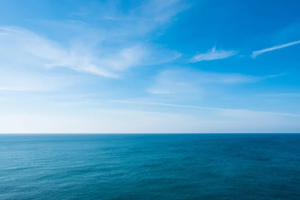 Cielo azzurro nuvoloso che parte per orizzonte sopra una superficie azzurra del mare — Foto Stock