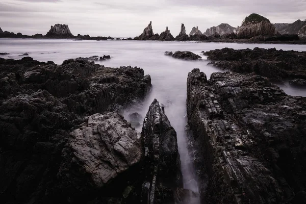 Avond Atlantische Oceaan kust landschap. Strand Gueirua met scherpe eilandjes. Asturias, Spanje. — Stockfoto