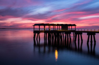 A beautiful ocean dramatic sunset and fishing pier at Jekyll Island in coastal Georgia, USA. clipart