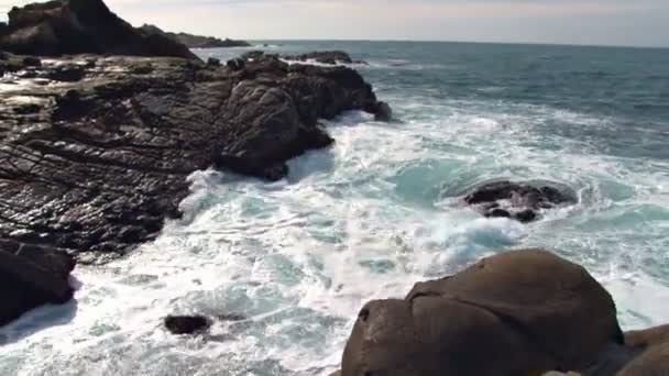 Хвилі падають на скелі на березі — стокове відео