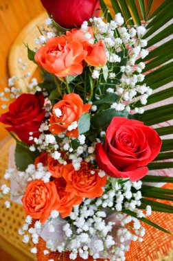 Serpiştirilmiş beyaz çiçekli bir buket kırmızı ve sarı güller.