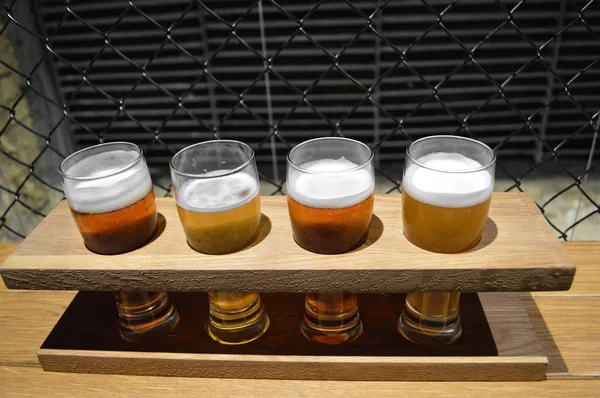 Czterech szklanek piwa w drewniany stojak — Zdjęcie stockowe