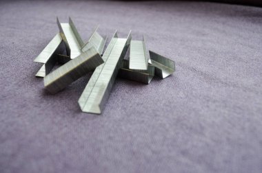 Demir, metal, Simli zımba mor bez arka planı bir yığın halinde yığılmış.