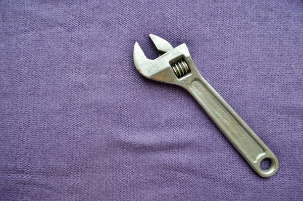Металл Железо Блестящий Регулируемый Гаечный Ключ Фоне Фиолетовой Ткани Инструменты — стоковое фото