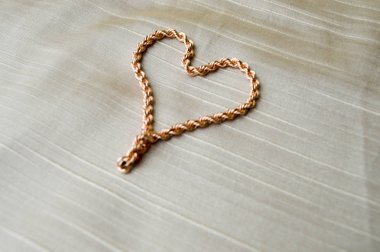 Kalp altın zinciri yaptı. Bej renkli arka plan üzerinde mücevher parlak, parlak, göz alıcı, moda, pahalı yürekten.