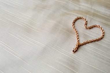 Altın kadınların zinciri, bilezik kalp şeklinde. Mücevher parlak, ışıltılı, çekici, şık, pahalı yürekten Sevgililer gününde bir arka plan bej kumaş için.