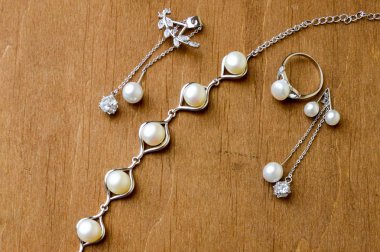 Güzel yüzük, kolye, küpe, takı ile değerli taşlar, inciler kahverengi ahşap arka plan üzerinde.