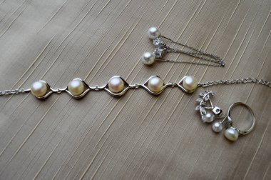 Güzel yüzük, kolye, küpe, takı ile değerli taşlar, inciler arka plan bej kumaş üzerinde.