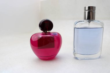 Kolonya iki güzel cam şeffaf parlak şık çekici şişeler, parfüm pembe ve mavi küçük kapaklar ve hafif beyaz arka plan üzerinde basit bir metin için yer.