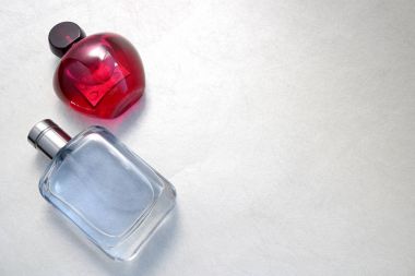 Kolonya iki güzel cam şeffaf parlak şık çekici şişeler, parfüm pembe ve mavi küçük kapaklar ve hafif beyaz arka plan üzerinde basit bir metin için yer.