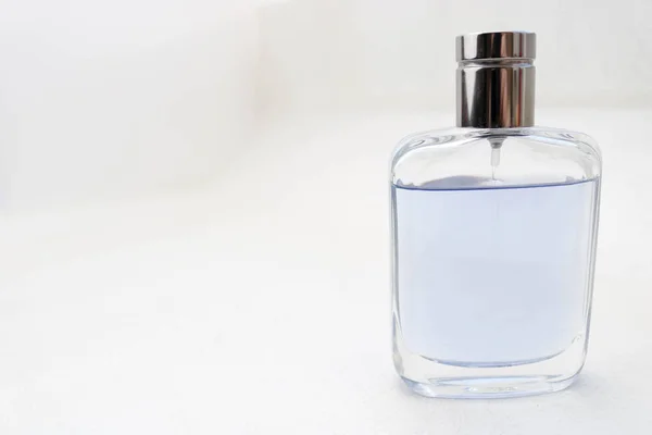 青い長方形の美しいガラス透明光沢のあるファッショナブルなケルンのファッショナブルなボトル 銀色のベゼルと灰色の光の背景にサンプルテキストのための場所と香水 — ストック写真