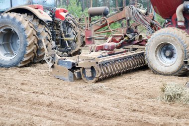 Bağlı ekme ünitesi, bir birleştirmek, bir tatbikat büyük tekerlekli traktör alan pulluklar, tahıl ürünleri sows, tarım, ağaçlar arka plan üzerinde çiftlik iş yapar.