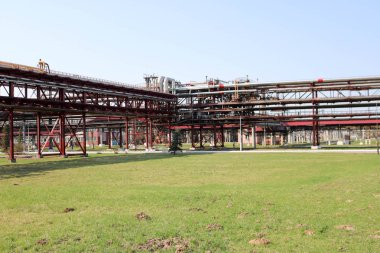 Çıkışları ve drenaj ile sıvı bir petrol rafinerisinde pompalama için demir Paslı boruları, Petrokimya, kimyasal bitki yeşil çimen, yatay bir arka plan ile boru hattı sehpa.