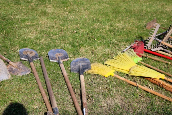 Birçok tırmık, kürek ve fırçalar bölge temizliği için yeşil çim üzerinde yalan