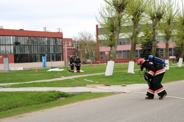 Profesyonel itfaiyeciler, insan bir yangın hortumu, bir hortum ile tehlikeden kurtarmak için kurtarma ekipleri yangına dayanıklı koruyucu giysiler, kask ve oksijen şişe ile gaz maskeleri hazırlanır.