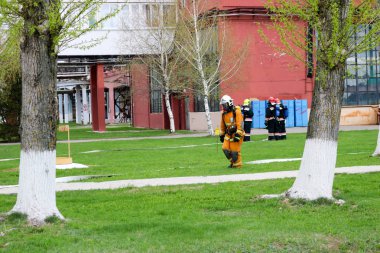 Profesyonel itfaiyeciler, insan bir yangın hortumu, bir hortum ile tehlikeden kurtarmak için kurtarma ekipleri yangına dayanıklı koruyucu giysiler, kask ve oksijen şişe ile gaz maskeleri hazırlanır.