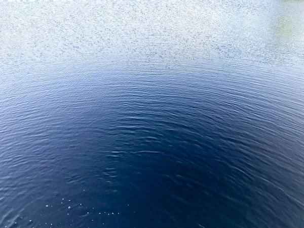 Mavi güzel su ve dairesel dalgalar waterdish yamalar, kabarcıklar ve sprey aşağıdan, arka plan doku.