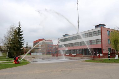 Gaz maskesi ile beyaz kask turuncu ateşe dayanıklı elbiseli profesyonel itfaiye yangın söndürme ve ateşli silahlar binaların arka planda yaşıyoruz.