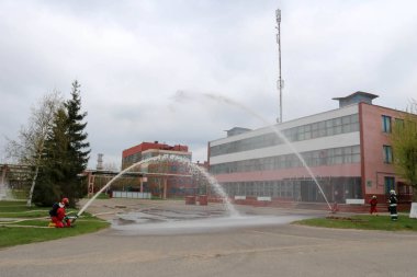Gaz maskesi ile beyaz kask turuncu ateşe dayanıklı elbiseli profesyonel itfaiye Yangın hortumlar test ve bir petrol rafinerisi yangın söndürmek için ateş.