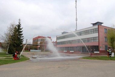 Gaz maskesi ile beyaz kask turuncu ateşe dayanıklı elbiseli profesyonel itfaiye Yangın hortumlar test ve kimyasal Rafinerisi'nde yangın söndürmek için ateş.