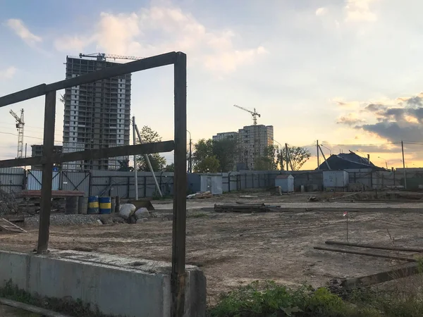 Vista interior de una gran obra de construcción industrial detrás de una valla con herramientas, cañones y materiales de construcción sobre los que se están construyendo nuevas casas. — Foto de Stock