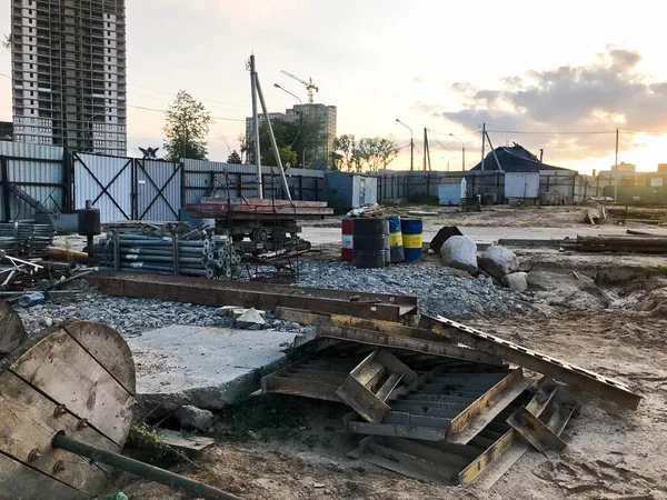 Vista interior de una gran obra de construcción industrial detrás de una valla con herramientas, cañones y materiales de construcción sobre los que se están construyendo nuevas casas. — Foto de Stock