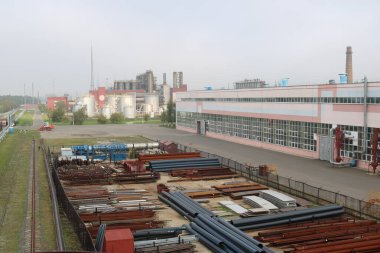 Demir metal boruları ve teknik ekipmanları fabrikada depolamak için açık havada büyük bir sanayi deposu var.