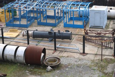 Demir metal boruları ve teknik ekipmanları fabrikada depolamak için açık havada büyük bir sanayi deposu var.