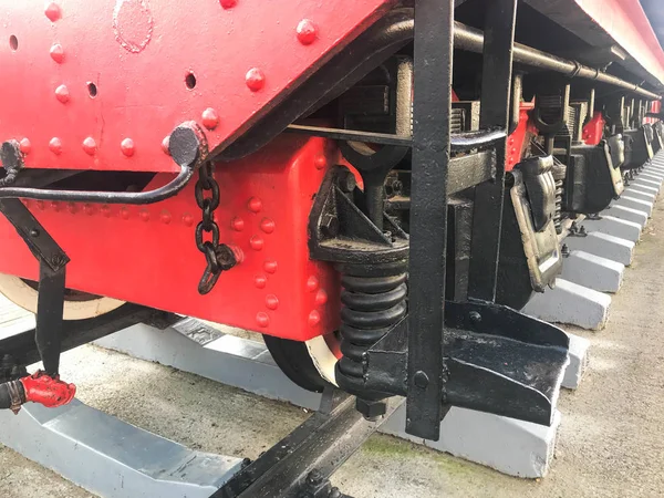 Grote ijzeren wielen van een rode en zwarte trein op rails en ophangelementen met veren van een oude industriële stoomlocomotief — Stockfoto