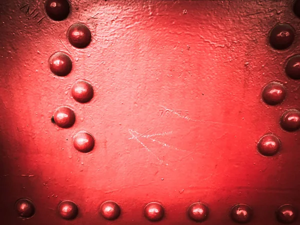 Red iron metal rough painted strong solid industrial wall with rivet holes and bolts. Background, texture