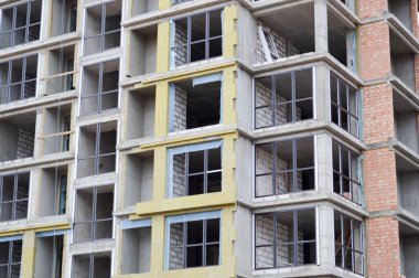 Pencereleri ve aksesuarları, pencereleri, duvarları ve balkonları olan, inşaat halindeki yeni ve modern bir monolitik yapı bloğu. Arkaplan, doku