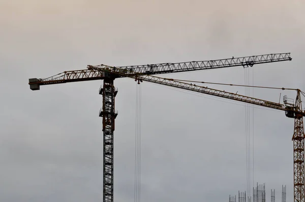 Gran grúa industrial de carga de construcción potente en un sitio de construcción de nuevos edificios y casas contra el cielo —  Fotos de Stock