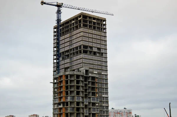 Grande grue industrielle à cargaison puissante sur un chantier de construction de nouveaux bâtiments et maisons contre le ciel — Photo