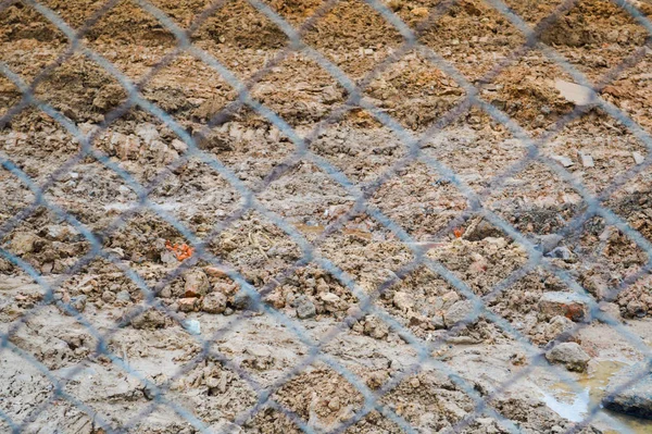 Vue de la terre brune à travers un filet de treillis métallique en osier. Le fond. Texture — Photo