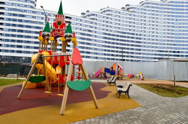 Şehrin yeni bir bölgesinde, yeni bir binanın avlusunda, spor aletleri ve oyuncaklarla açık havada yeni ve modern bir açık hava oyun alanı.