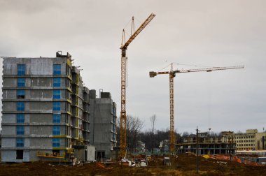 Endüstriyel inşaat ekipmanları ve büyük vinçler kullanılarak büyük modern monolitik çerçeve evler inşa ediliyor. Binanın inşaatı şehrin yeni mikro bölgesinde.