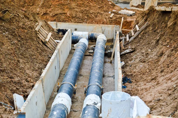 Yerin altındaki yeni bir mahallede yapılan onarım sırasında inşaat alanında sıcak ve soğuk su için büyük siyah metal ve plastik su boruları.